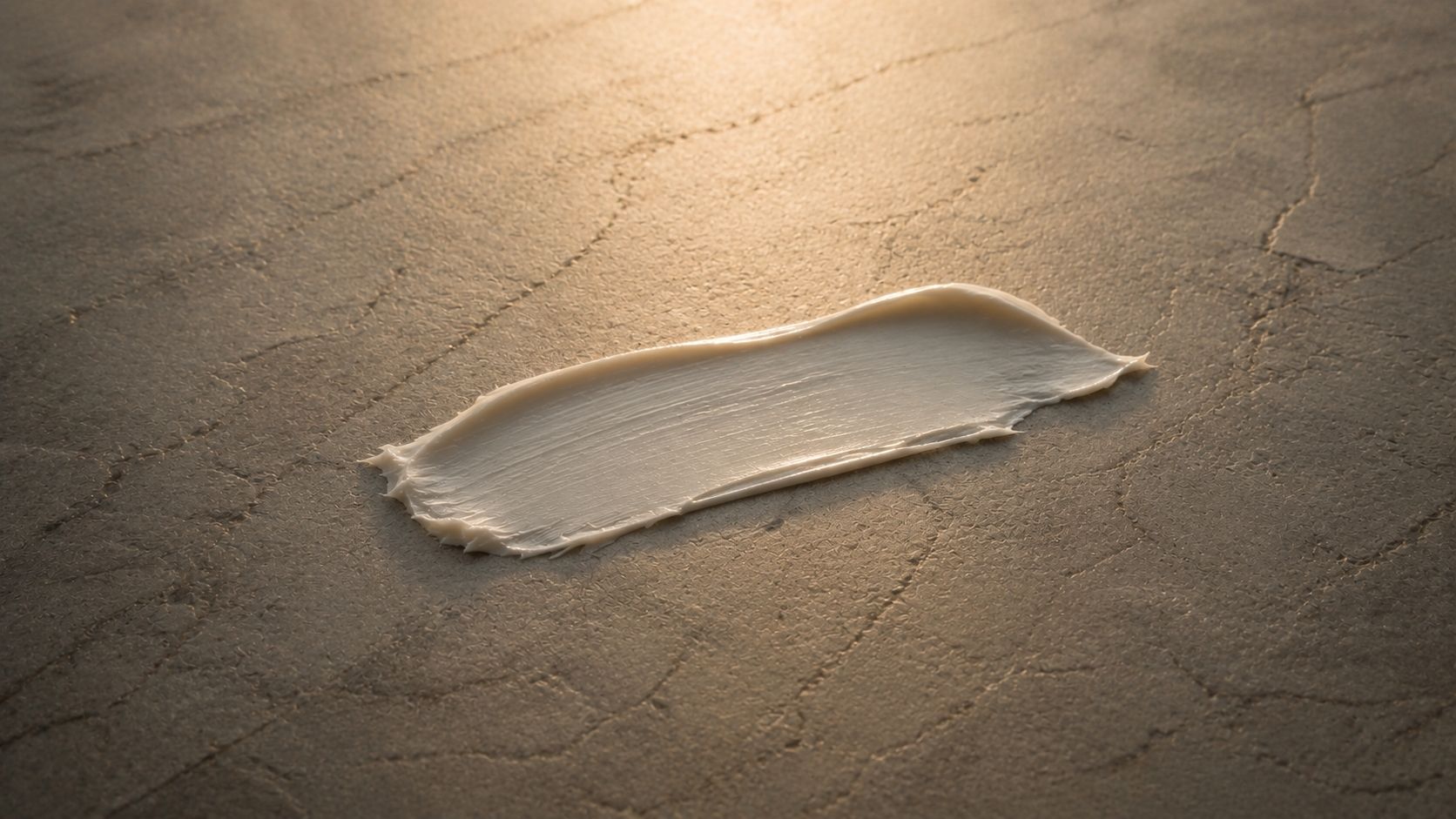 Minimalist skincare texture shot of white cream spread across a matte stone surface in soft natural backlight, warm neutral tones and tactile cosmetic detail in an editorial still life composition.